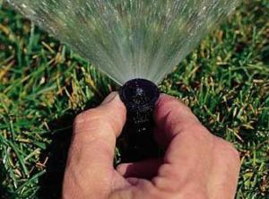 a Woodbridge Irrigation Repair specialist tweaks a pop up head
